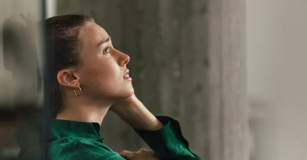 Woman sat on floor with back against the wall looking slightly distressed